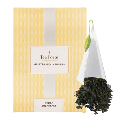 Box of Tea Forte pyramid infusers with a hanging tea bag and loose tea leaves on a white background