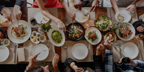 People sharing a meal at a table with various dishes and utensils.