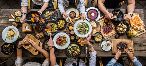 Top-down view of a table with various dishes and people around it, likely at a restaurant.