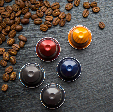 Coffee capsules and coffee beans on a dark surface